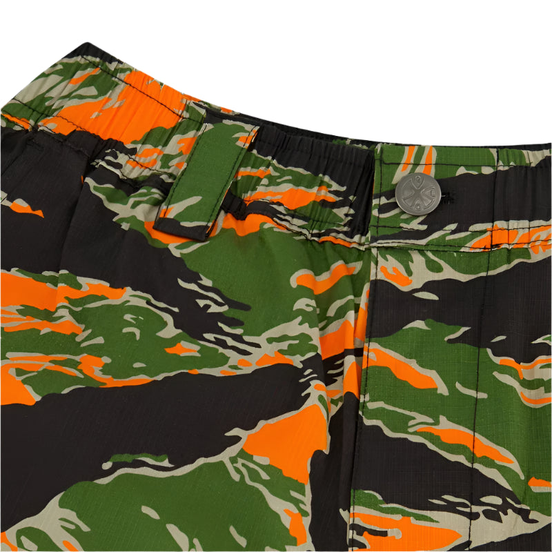 Close-up of tiger stripe camouflage-patterned shorts with blaze orange, green, and black colors. Noveske x Qilo logo on the button