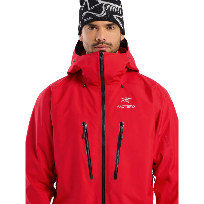 Close up view of the Arc'teryx Alpine Guide Jacket in Dynasty II red showing the chest pockets, radio ready storage, and professional ski guide GORE TEX PRO construction featured in the Arc'teryx on sale collection.