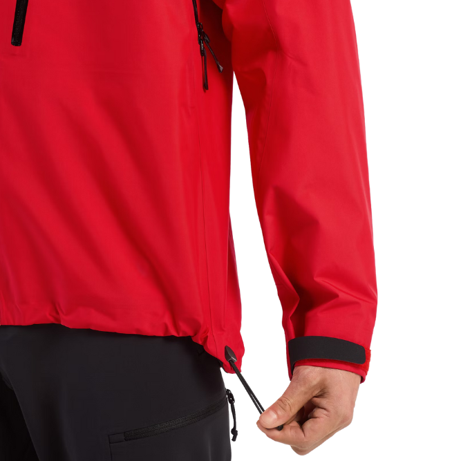 Close view of the Arc'teryx Alpine Guide Jacket in Dynasty II red showing the elastic waist cinch and Cohaesive adjustment system on the professional ski guide GORE TEX PRO winter shell featured in the Arc'teryx on sale collection.