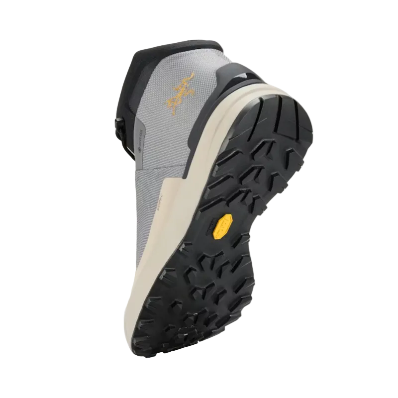 Gray hiking boot with black sole and yellow Arc'teryx logo on a beige background