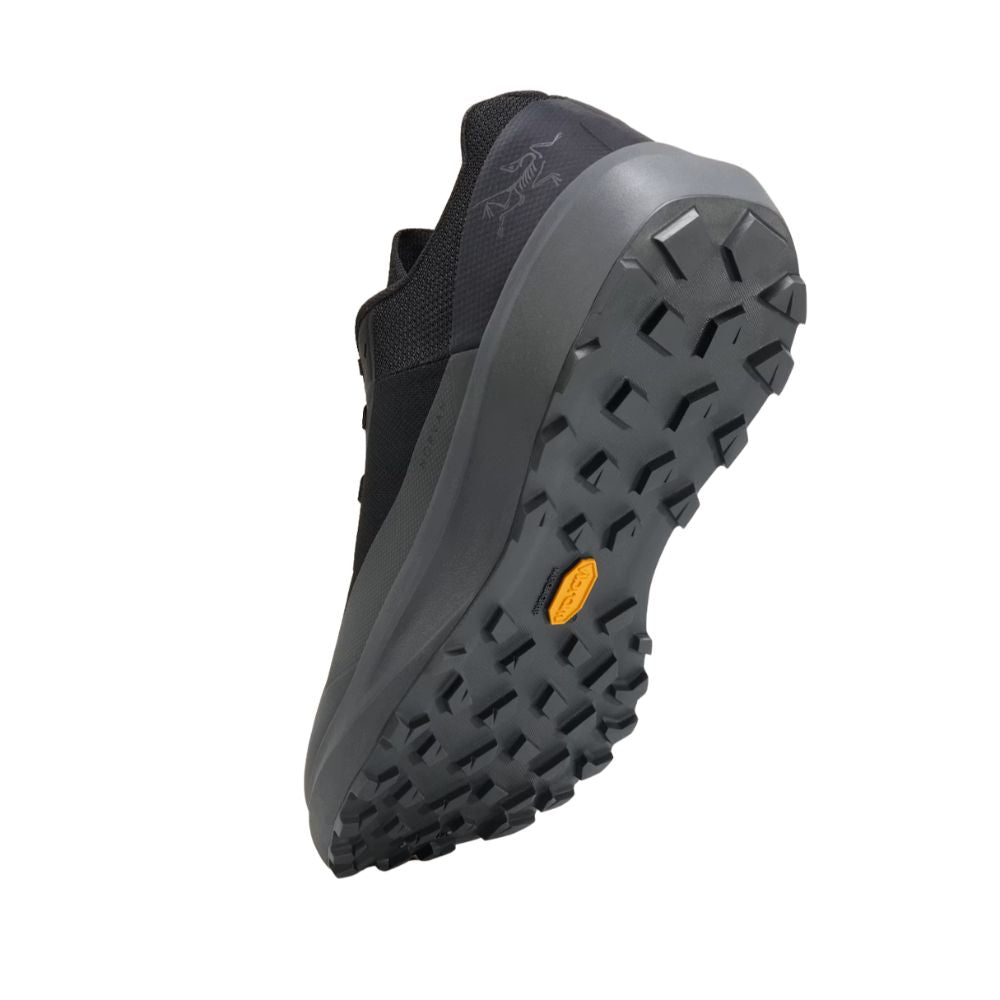Angled bottom view of the Arc'teryx Norvan LD 4 in Black/Graphite showcasing the Vibram Megagrip outsole with aggressive 4mm trail lugs.