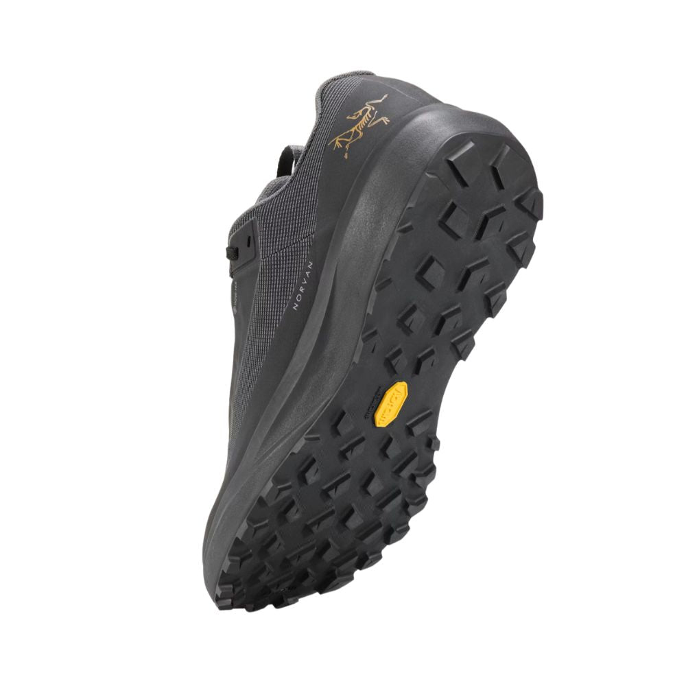 Angled bottom view of the Arc'teryx Norvan LD 4 GTX in Black/Black showcasing the Vibram Megagrip outsole with aggressive 4mm trail lugs.