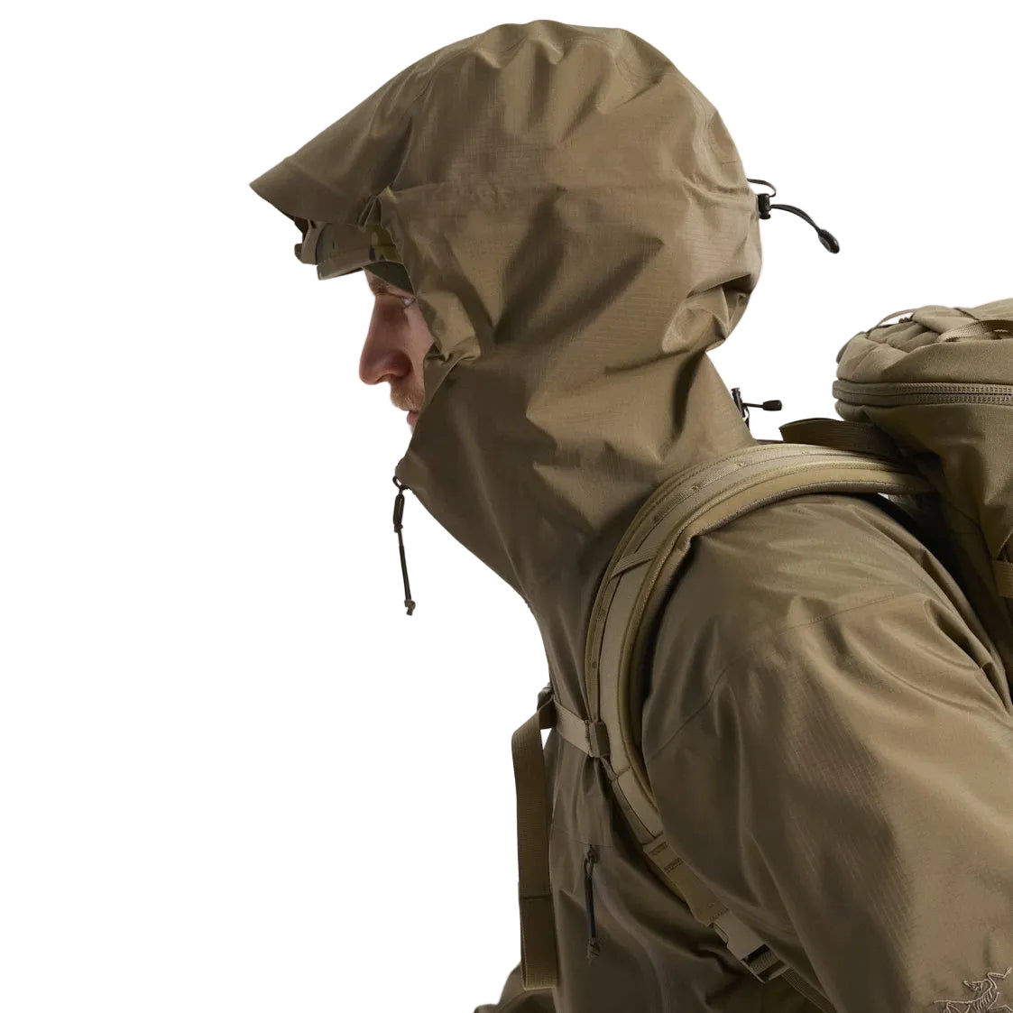 Side view of the Arc'teryx PRO Alpha LT Jacket Gen 2.2 in Crocodile worn with the hood up, highlighting the fixed hood design, streamlined military fit, and lightweight GORE TEX 3 layer protection. This PRO-series shell, evolved from the Arc'teryx LEAF line, is built for wet weather tactical movement and high mobility field performance.