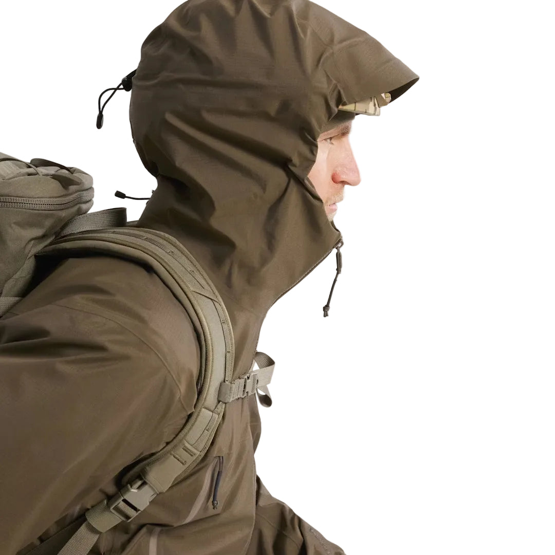 Side view of the Arc'teryx PRO Alpha LT Jacket Gen 2.2 in Ranger Green worn with the hood up, highlighting the hood adjustment points, streamlined fit, and lightweight GORE TEX 3 layer construction. The PRO Alpha LT, evolved from the Arc'teryx LEAF line, is designed for precise weather protection and high mobility in tactical environments.