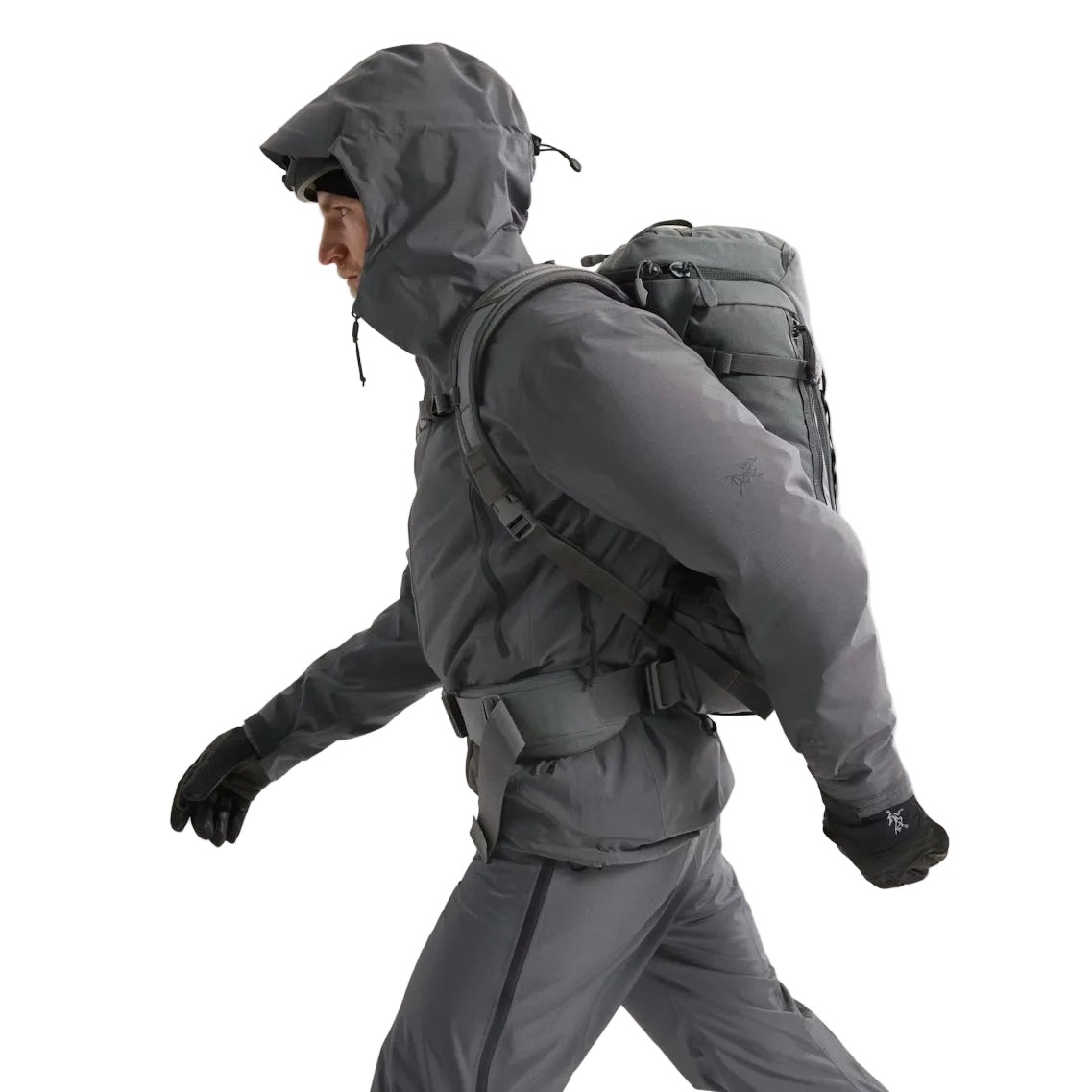 Side view of the Arc'teryx PRO Alpha LT Jacket Gen 2.2 in Wolf Grey being worn with the hood up, showing the Arc'teryx arm logo placement, streamlined military fit, and lightweight GORE TEX 3 layer construction. This PRO-series design, evolved from the Arc'teryx LEAF line, delivers mobility, weather protection, and low-profile performance for tactical field environments.