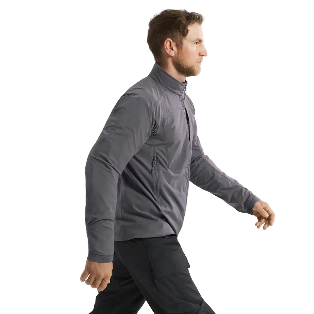 Side view of the Arc'teryx PRO Practitioner AR Jacket in Wolf Grey being worn, showing the articulated patterning, streamlined Fortius Air 50 shell, and low-bulk Octa Loft insulation. Ideal for users researching how the Practitioner AR fits in motion, layers under gear, and performs as a breathable tactical mid layer for field operations, range use, and harsh-weather mobility.