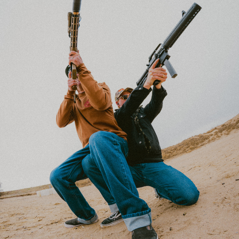 Two people in a desert-like setting holding rifles.