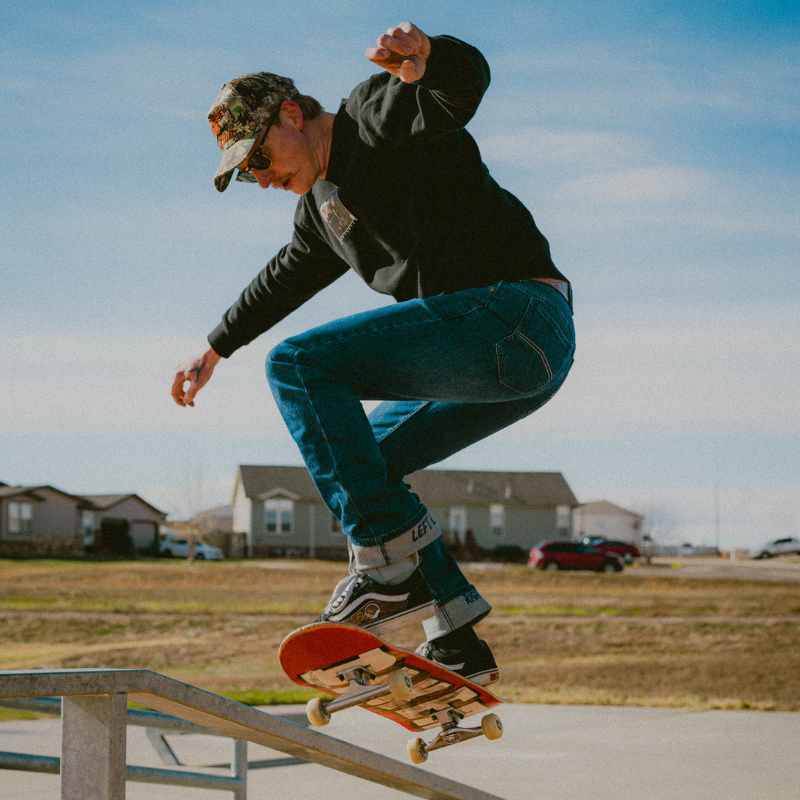 Person skateboarding on a rail with houses and cars in the background