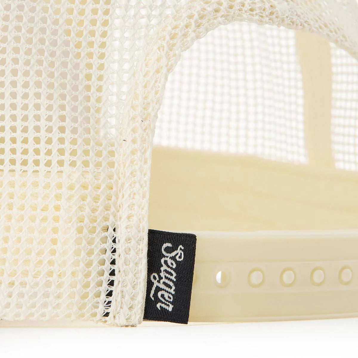 Close-up of a mesh trucker hat with a Seager brand label on a white background