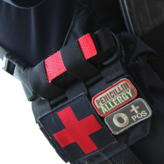 Blue Force Gear Tourniquet NOW Strap securing a CAT tourniquet to a tactical kit alongside magazine pouches, providing rapid-access medical gear retention on a MOLLE loadout.