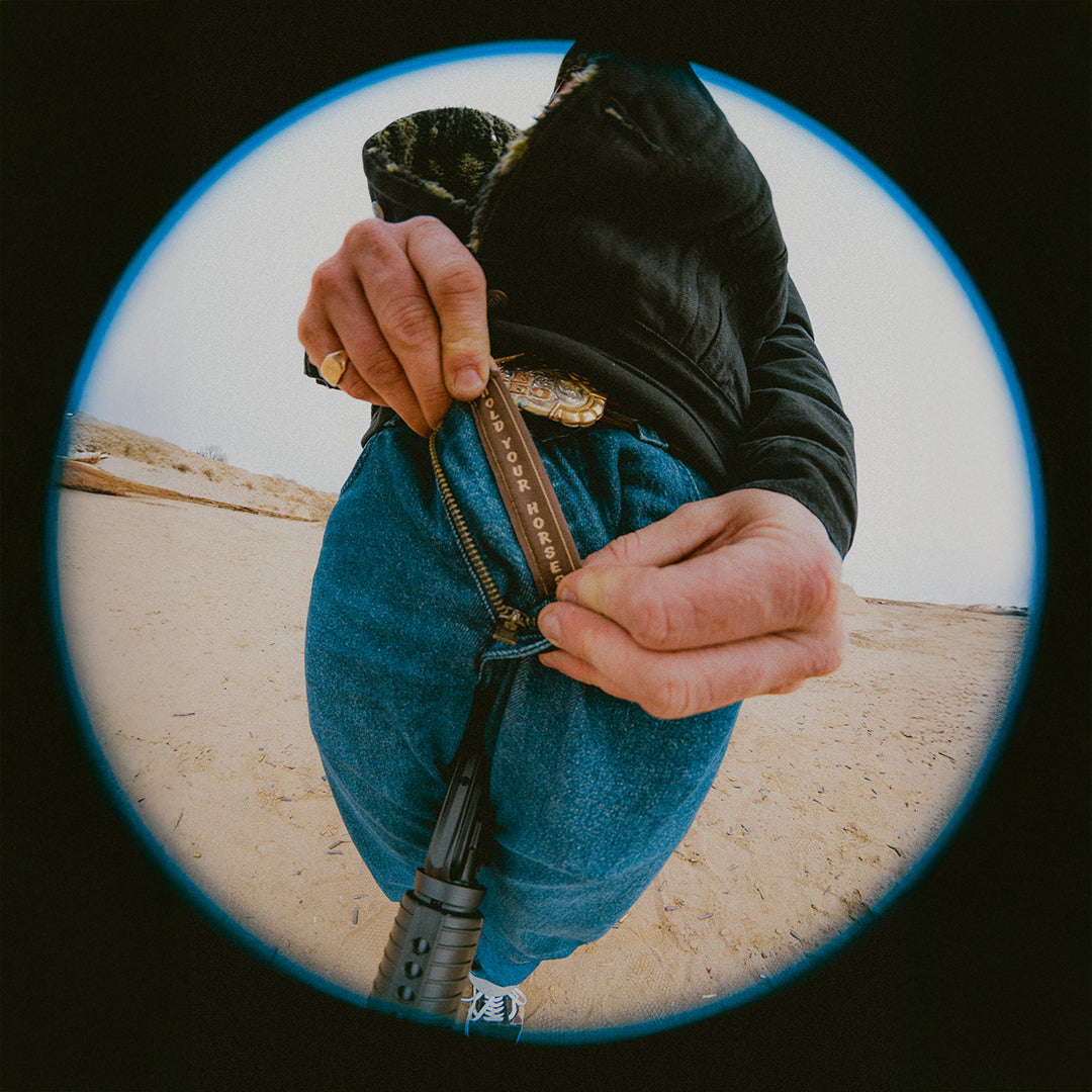 Person adjusting a zipper that says "Hold your Horses" on a blurred background