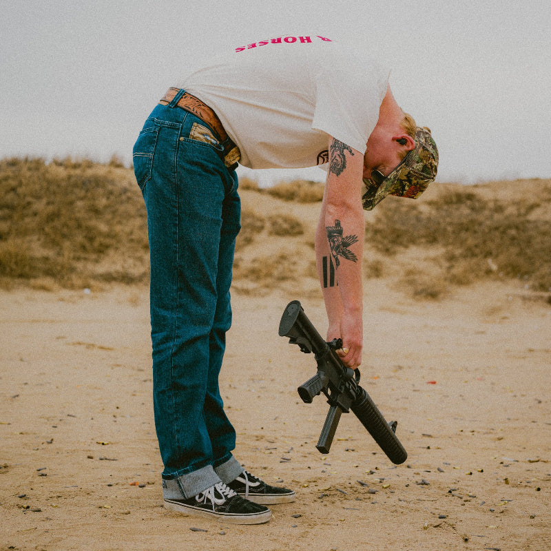 Person holding a rifle in a desert-like setting