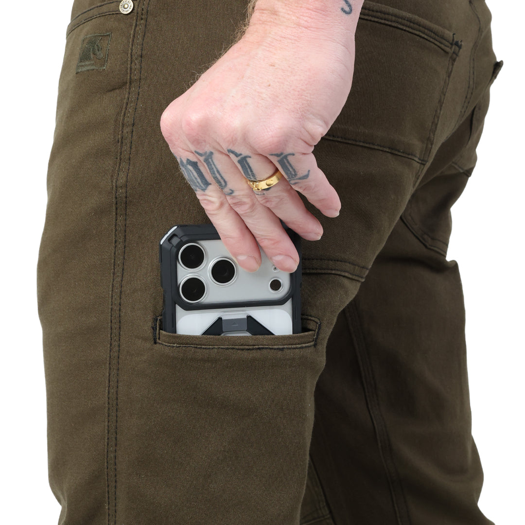 Close-up of the Carlos Ray V3 Tactical Pants in Ranger Green Slim Fit showing the low-profile thigh pocket used for phone carry, sized to also fit most pistol magazines for EDC or range use. Highlights reinforced openings and 4-way stretch twill construction. Also available in Regular Fit for users who prefer a roomier tactical pant.