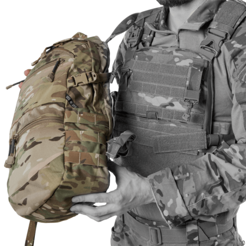 Crye Precision AVS 1000 Pack held against a plate carrier to show approximate size and profile, modular tactical assault pack compatible with Crye AVS and JPC systems designed for low profile mission ready hydration and gear carry