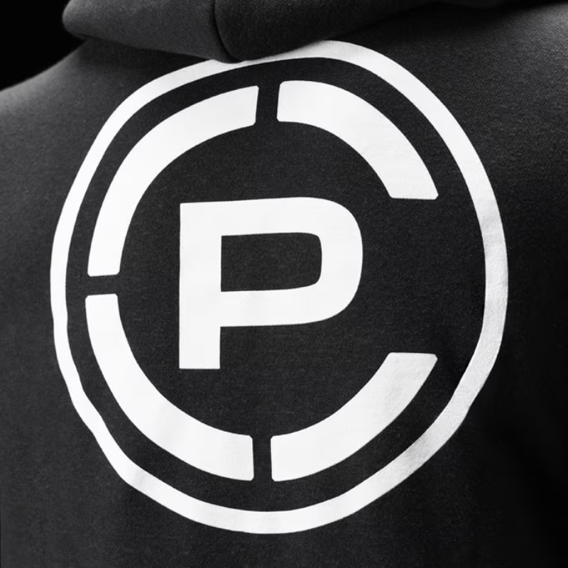 Close-up of a black hoodie featuring a large white circular graphic with a stylized letter CP in the center.