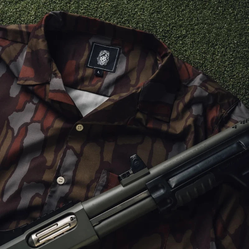 TreebarkCamouflage jacket with a brand logo and a shotgun on a grassy background