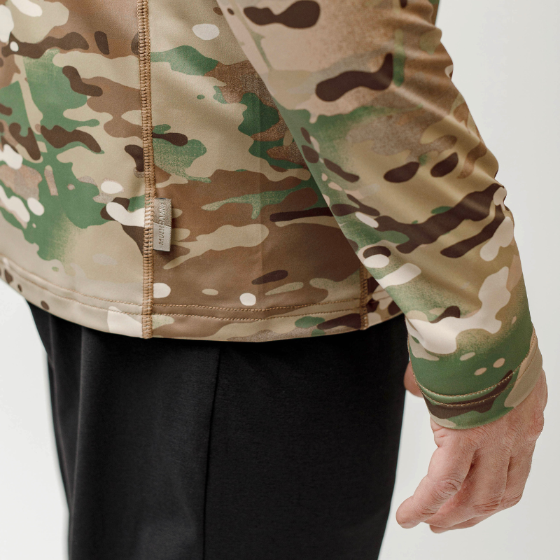 Detailed view of official MultiCam pattern tag and flat-lock stitching on the tactical range shooter shirt, highlighting authenticity and comfort seams
