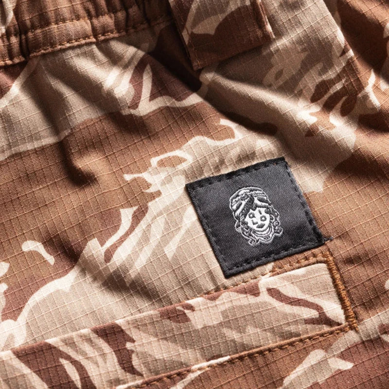 Desert Tiger Stripe Camouflage shorts with a QILO x WRMFZY brand logo patch on a white background