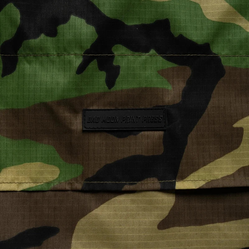 M81 Woodland Camouflage fabric with a Bad Moon Print Press brand label in the center
