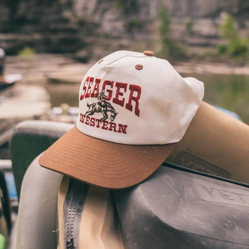 Seager cap on some YETI bags with a scenic background of a lake and mountains.