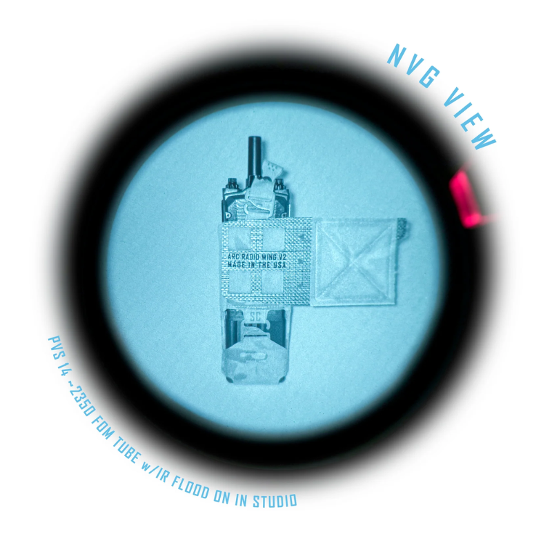 A circular black-framed view through a blue-tinted optical tube, showing a small mechanical component and tape-wrapped part. Blue text reads 'NVG VIEW' and 'PVS 44 - 2500 FM TUBE w/IR FLOOD ON IN STUDIO'.