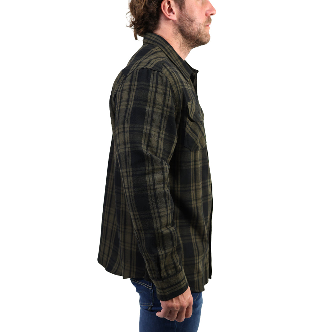 A man shown in profile wearing a dark green and black plaid flannel shirt with blue jeans, photographed against a solid white background.