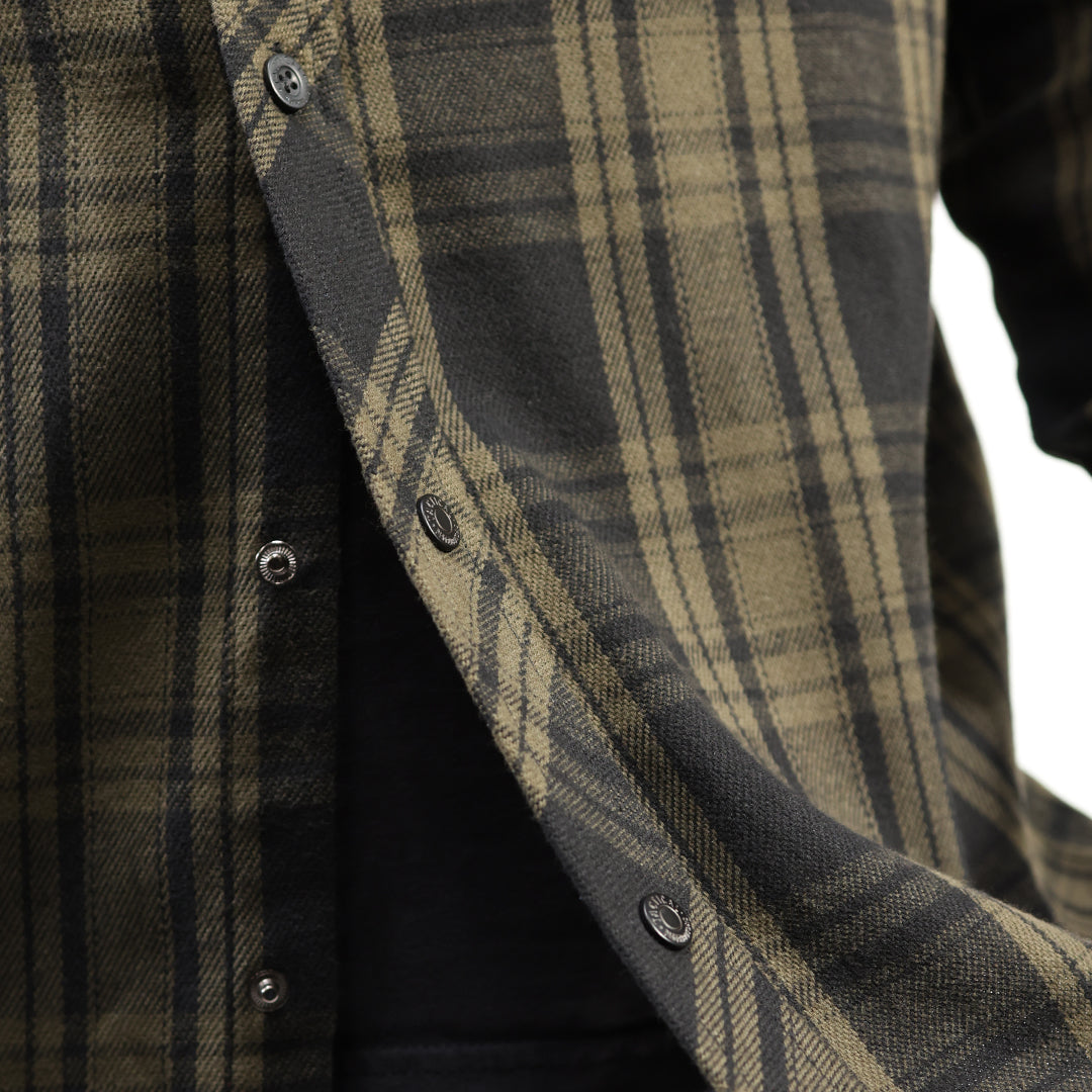 Close-up of a plaid button-front shirt in dark olive green and black, with visible buttons and a black undershirt underneath.