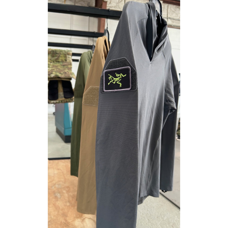 TD OSS Operator Shooter Shirt displayed hanging with a unit patch attached to the arm loop field, showcasing the tactical functionality for ID or morale patches. This performance base layer combines four-way stretch, moisture-wicking fabric, and operator-ready features ideal for range days and mission wear