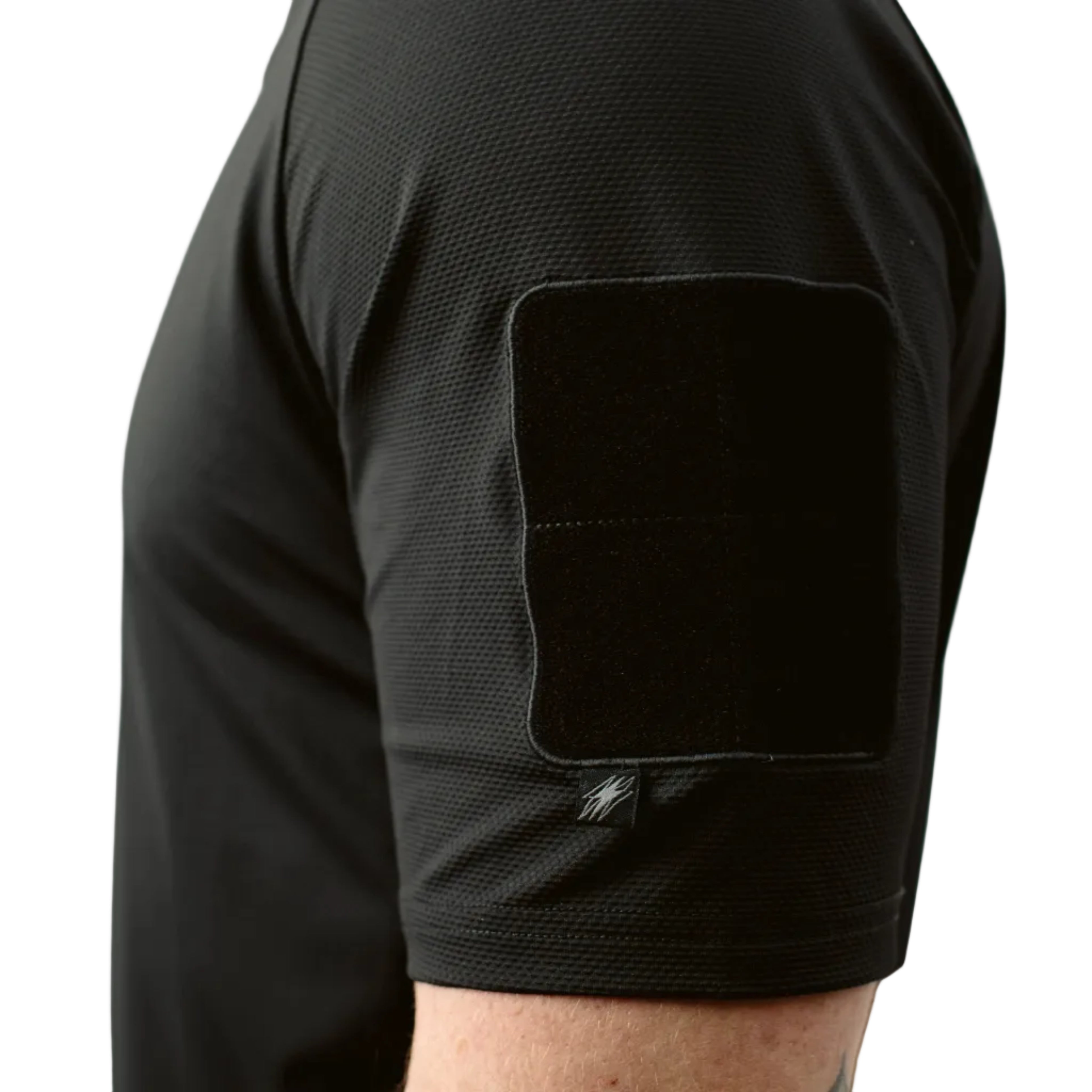 Close up of TD OSS Top Short Sleeve in Black showing low profile bicep loop patch field and articulated raglan sleeve detail, lightweight tactical range shirt and combat base layer built for hot weather training, operator use, and duty wear under plate carriers