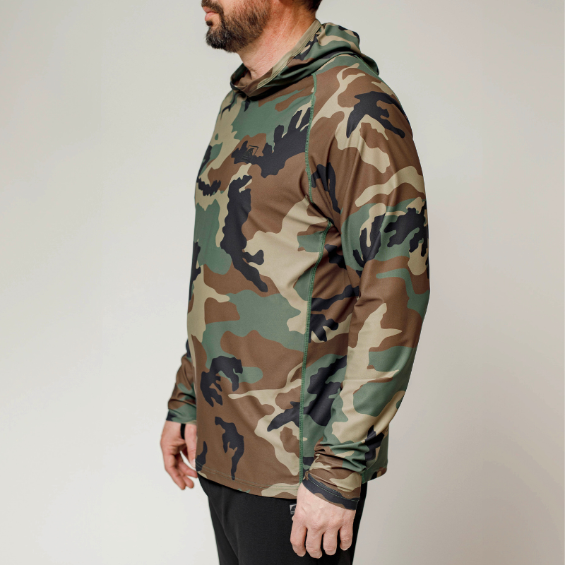 Three-quarter view of the TD Outdoor Tiger Shark Sun Shirt 3.0 in Woodland camo, highlighting flatlock stitching, sleeve construction, and tactical fit.