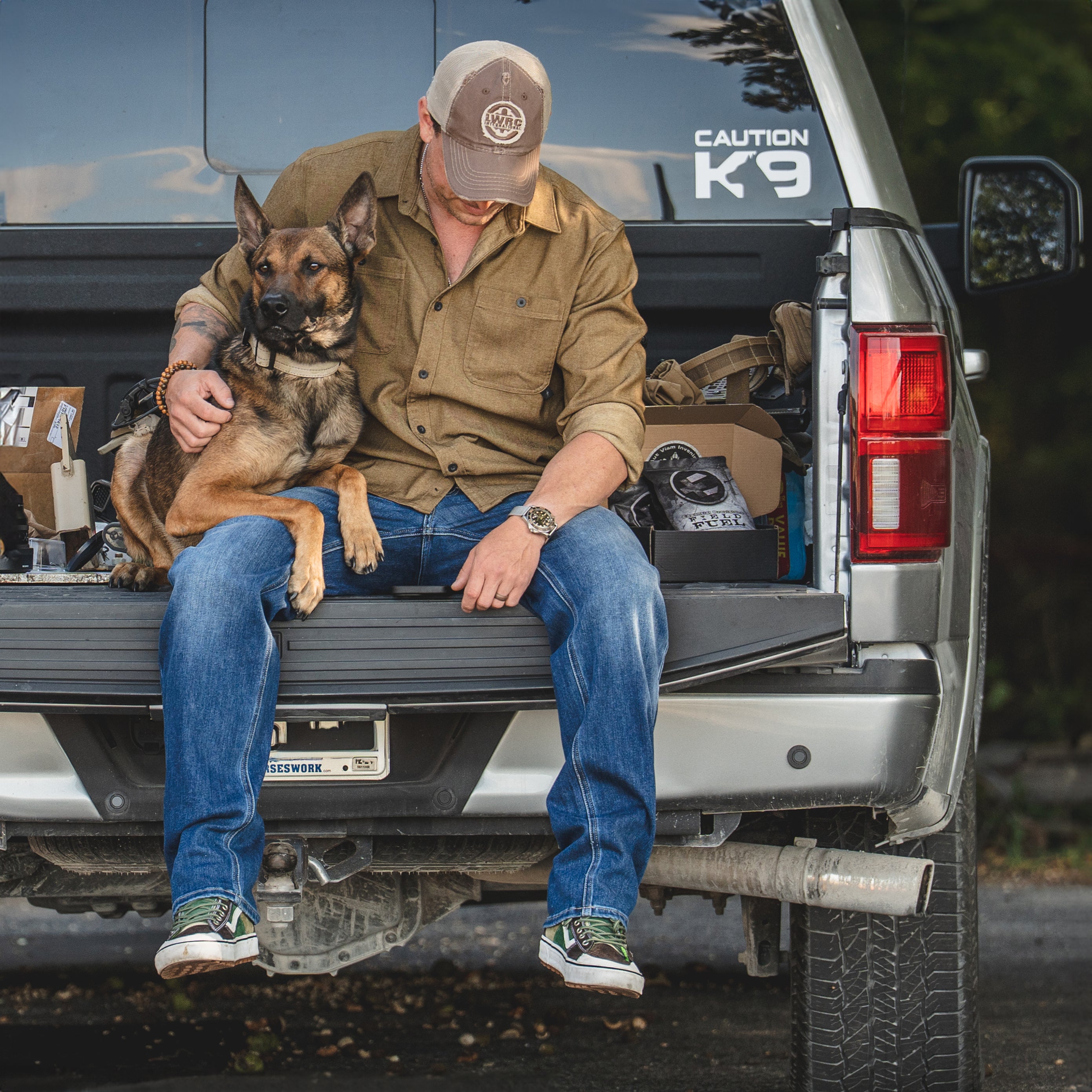 Lifestyle photo of a man outdoors with his truck and dog wearing the brass TD Stretch Flannel Work Shirt, a soft and comfortable tactical flannel built for all-around wear from Range Day to everyday work apparel.