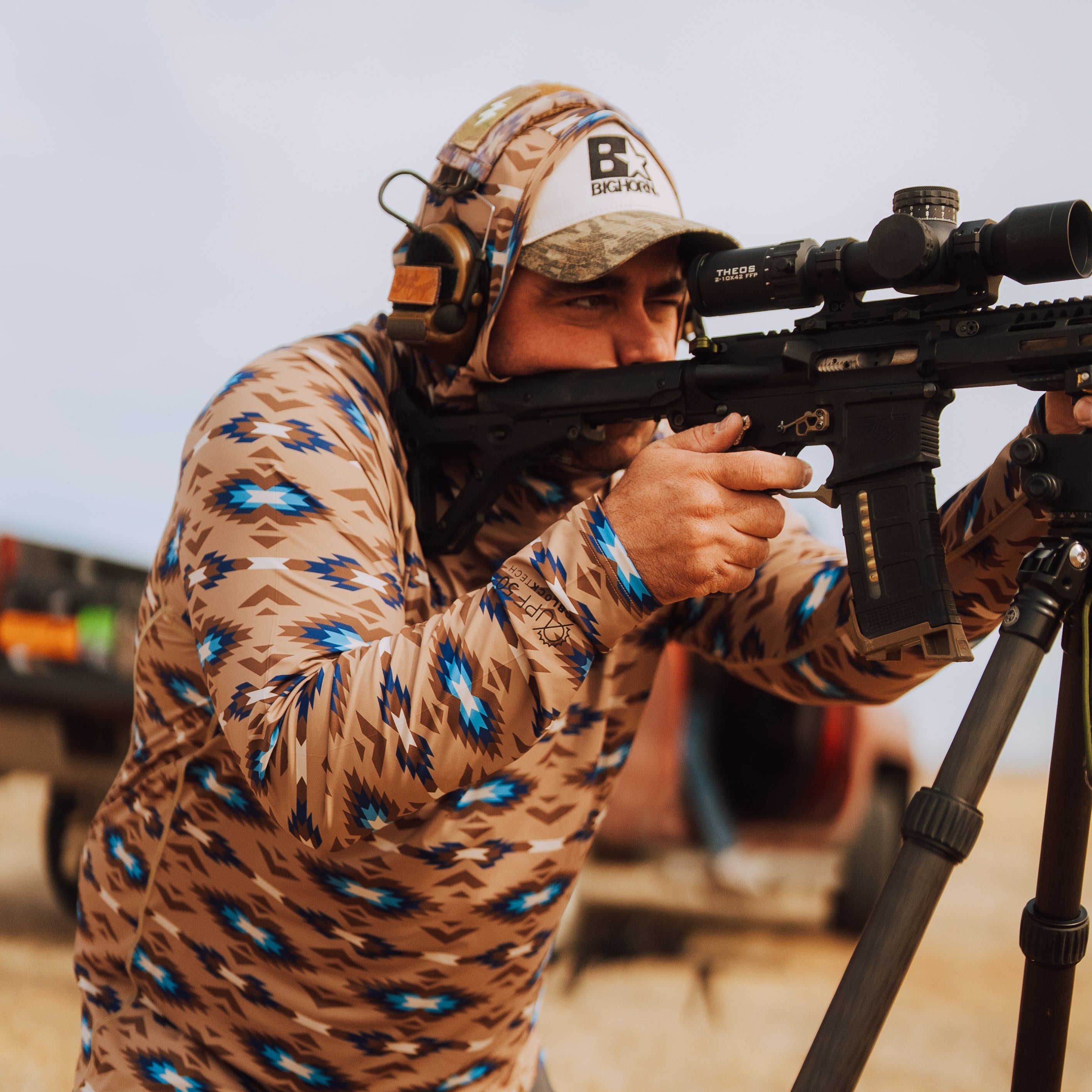 TD x Black Canyon Systems Southwest Tan tactical sun hoodie worn with hood up during live fire range training, high coverage UPF 50 hood protecting neck and head while shooting in hot weather conditions with breathable performance fabric