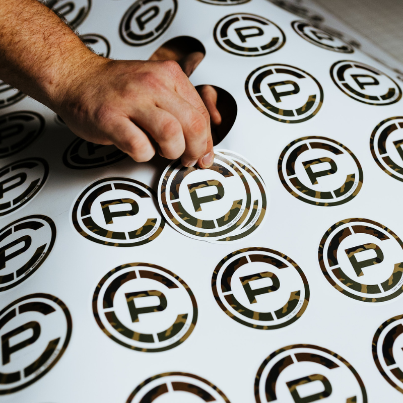 TD x Crye Precision M81 Woodland stickers being printed during a small-batch production run in Virginia Beach, showcasing the matte-finish collaboration design.