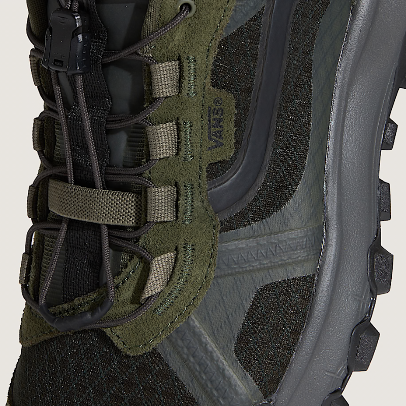 Close-up of a green and black hiking boot with brand logo on a beige background