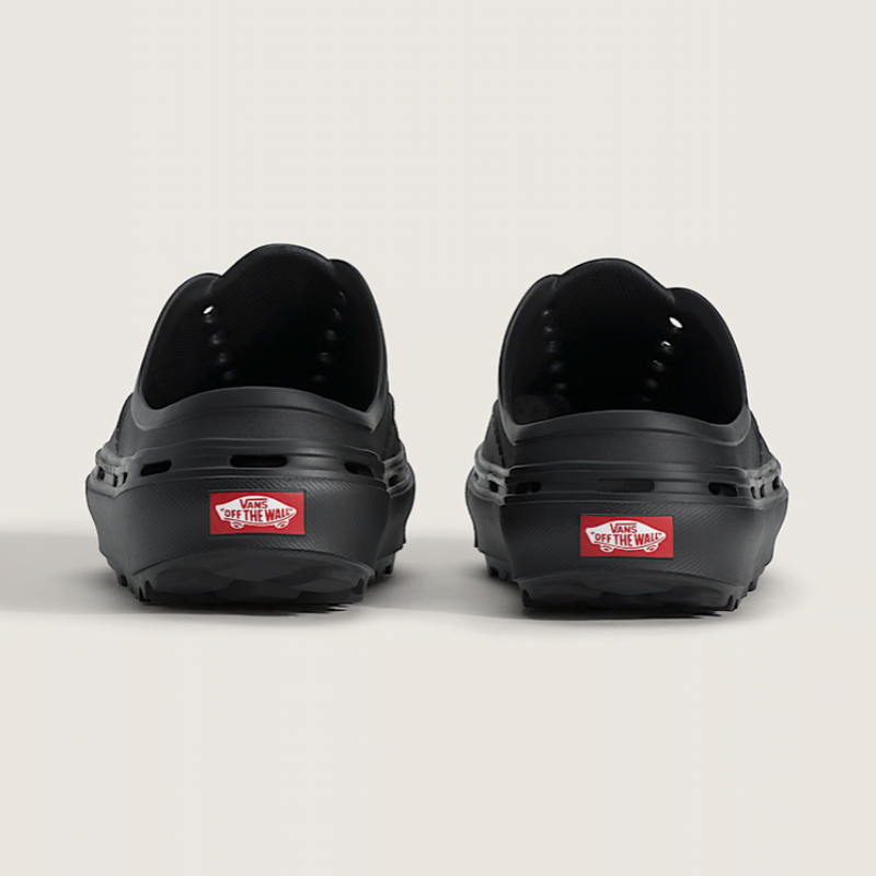 Black shoes with a red Vans label on the sole against a light gray background