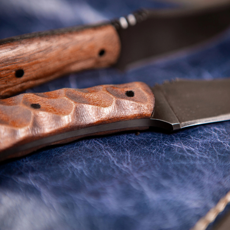Winkler SD1 maple handle variants shown together comparing smooth plain scales and contoured sculpted grip with trailing point blade and leather sheath carry system