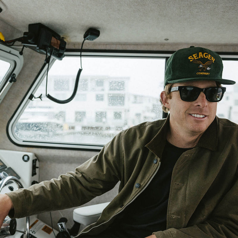 Man wearing a 'Seager Company' cap and sunglasses inside a vehicle.