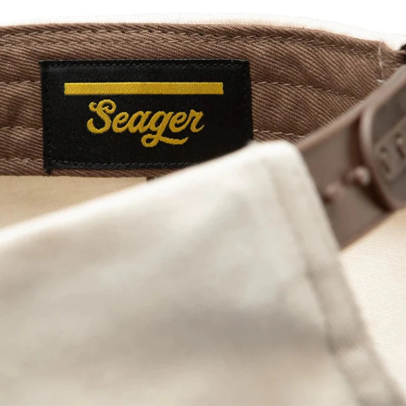 Close-up of a 'Seager' brand label on a cap with a beige background.