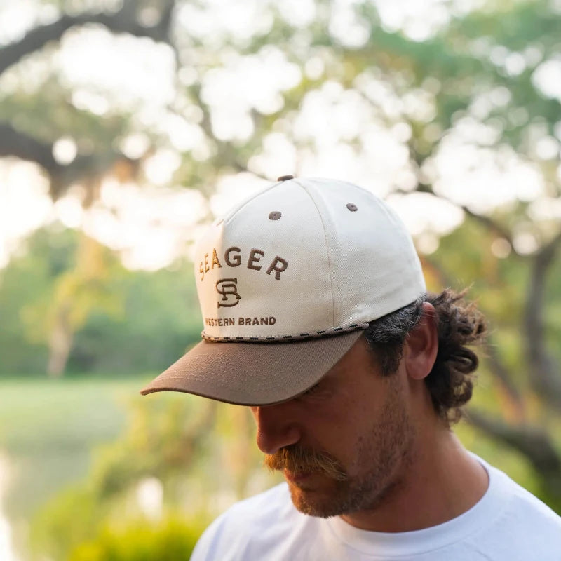 Man wearing a cap with 'Seager' branding outdoors
