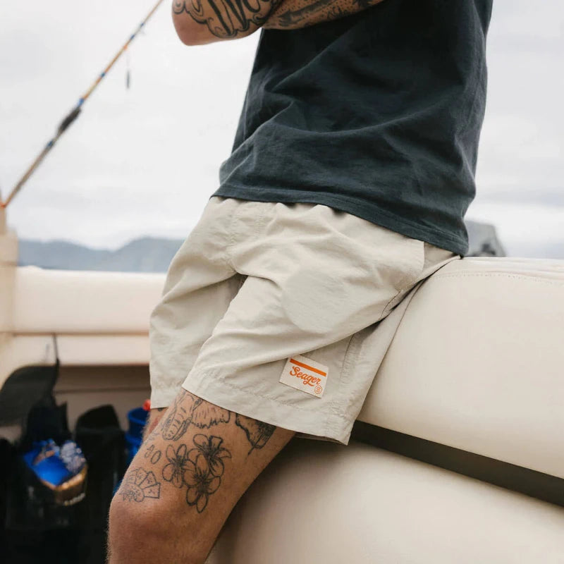 Person sitting on a boat wearing beige shorts with a brand logo.