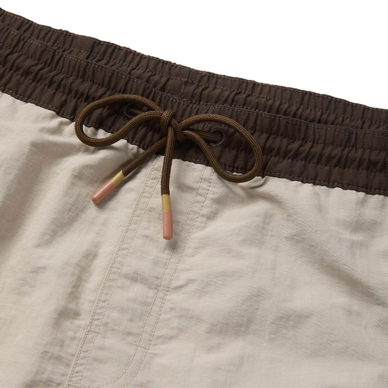 Close-up of beige shorts with a brown drawstring and colorful ends on a white background