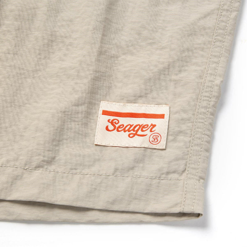 Close-up of a beige fabric with a 'Seager' brand label on a white background