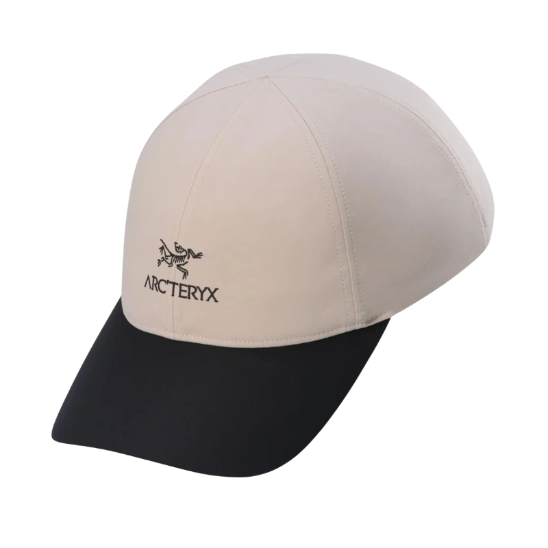 An Arc'teryx baseball cap featuring a light beige crown and a contrasting black curved brim, with the Arc'teryx logo embroidered on the front.