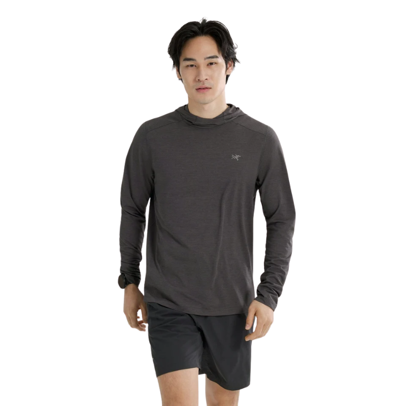 Male model wearing the Arc'teryx Cormac Hoody in dark grey with black shorts, showcasing the regular fit, long sleeves, and lightweight hooded design.