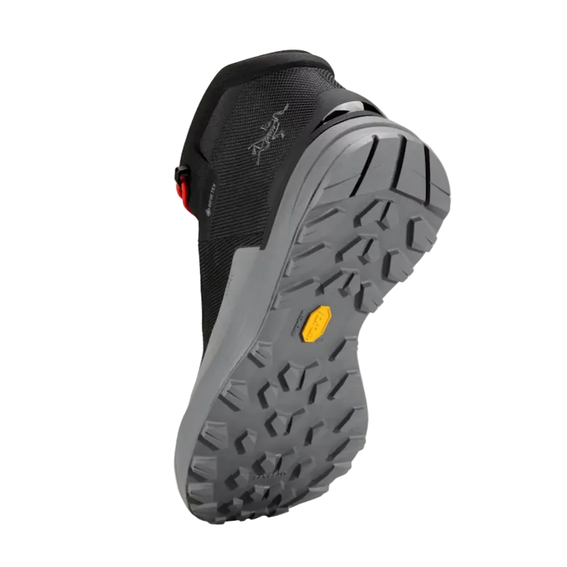 Black hiking boot with gray sole on a beige background