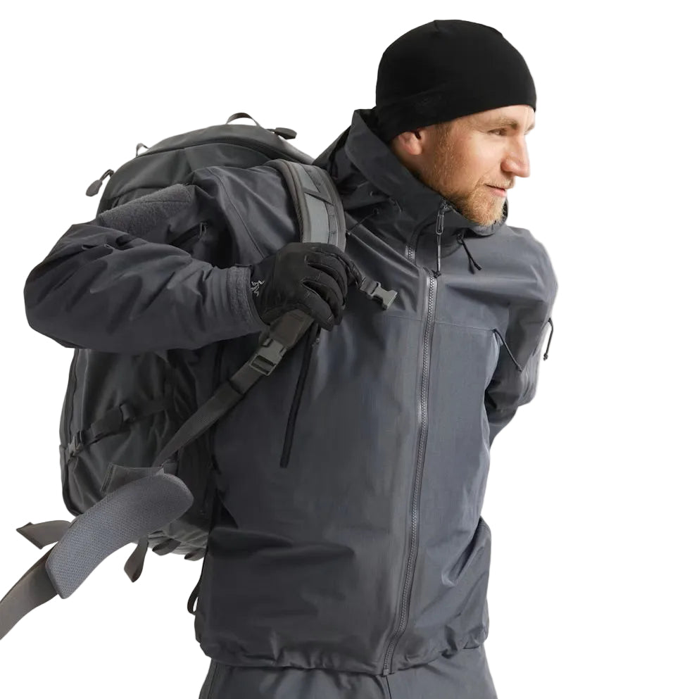 Image of the Arc'teryx LEAF Alpha Jacket Gen 2.2 in Wolf Grey being worn with a pack, highlighting the military fit, underarm venting, and GORE TEX waterproof protection designed for tactical operations, law enforcement, and field use across the United States.