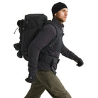 Arc'teryx PRO Practitioner AR Jacket in Black being worn with a tactical kit and backpack, highlighting its Fortius Air 50 breathable shell, Octa Loft insulation, and articulated mobility under load. Shows how the PRO-series mid layer integrates with plate carriers and packs for field operations, high-output movement, and mission-ready performance.