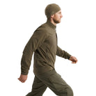 Side view of the Arc'teryx PRO Practitioner AR Jacket in Ranger Green being worn, highlighting the articulated patterning, streamlined Fortius Air 50 shell, and low-bulk Octa Loft insulation. Shows how the PRO-series mid layer enables unrestricted movement for users comparing tactical mobility, layering compatibility, and performance in field conditions or high-output environments.