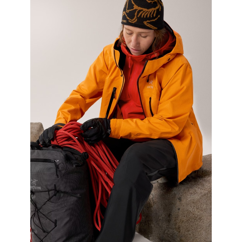 On body view of the Arc'teryx Women’s Practitioner AR Hoody in the Dynasty red colorway worn under a shell jacket showing its role as a lightweight Octa Loft insulated alpine mid layer featured in the Arc'teryx on sale collection.