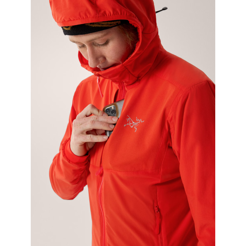 On body view of the Arc'teryx Women’s Practitioner AR Hoody in the Dynasty red colorway showing the front pocket in use and highlighting the Octa Loft insulated alpine mid layer featured in the Arc'teryx on sale collection.